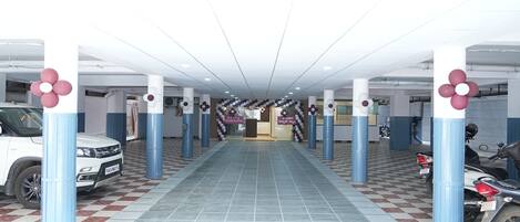 Un garaje para estacionamiento con piso a cuadros, columnas decoradas con flores y vehículos aparcados.