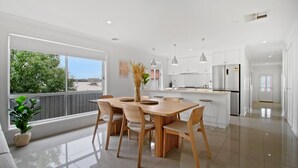 Una cocina moderna con armarios blancos, una isla central e iluminación colgante.