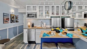 Una cucina moderna con mobili bianchi, un forno a microonde, una macchina per caffè e un'area pranzo con una panca e un tavolo.