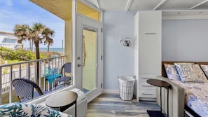 A balcony with a table, chairs, and a view of the beach.