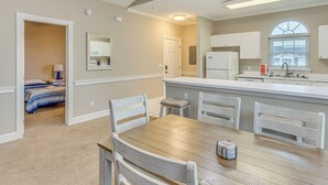 Una cocina con una mesa y sillas de madera, un refrigerador y una ventana con persianas.