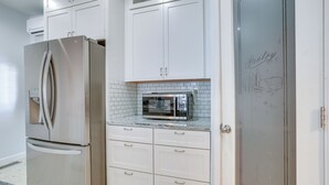 A modern kitchen with white cabinetry, a stainless steel refrigerator, a microwave, and a pantry door. - 4 Mi to Lake Logan: Hocking Hills Apartment (Logan)
