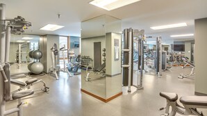 Ein Fitnessstudio mit unterschiedlichen Trainingsgeräten, einer Spiegelwand und einem sauberen, gut beleuchteten Innenraum.