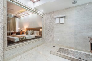 A modern bathroom with a large mirror, a shower area, and a visible bedroom with a bed and nightstand. - The Solitaire Resort by Lawrence Hotels (Mussoorie)