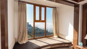 A room with a large window, curtains, and a view of a mountainous landscape. - The Solitaire Resort by Lawrence Hotels (Mussoorie)