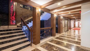 A grand staircase with marble steps and a wooden railing, leading to a second floor. - The Solitaire Resort by Lawrence Hotels (Mussoorie)