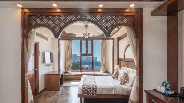 A hotel room with a large bed, a desk, and a view of the city. - The Solitaire Resort by Lawrence Hotels (Mussoorie)