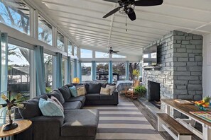 Relax in this stylish sunroom with a large sectional sofa, stone fireplace, and high ceiling.