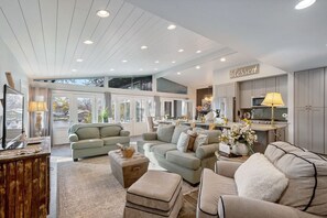 Relax in this inviting living area with a high ceiling, comfortable sofa set, and balcony offering a view of the surrounding landscape.