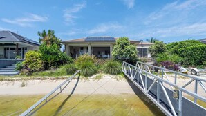 A coastal property with a bridge, a house with a solar panel, and a sandy beach.