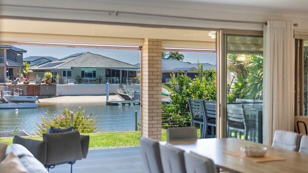 A modern outdoor dining area with a view of a swimming pool and a boat.