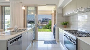 A modern kitchen with a dishwasher, stove, and a view to the outside.
