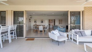 A modern living area with a dining table, sofas, and a sliding glass door leading to a kitchen.