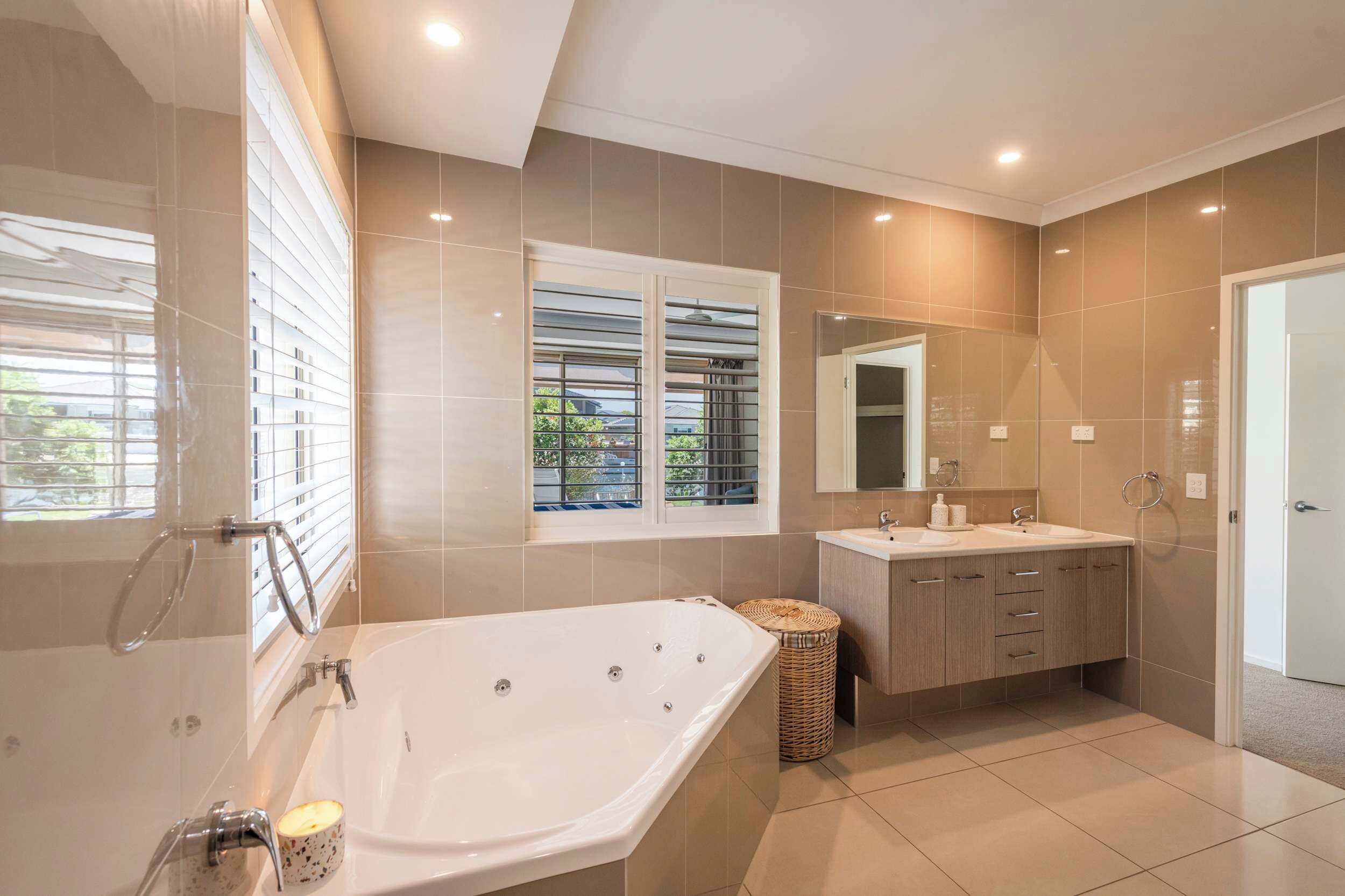 Une salle de bain moderne avec une baignoire, un meuble-lavabo et une fenêtre équipée de stores.