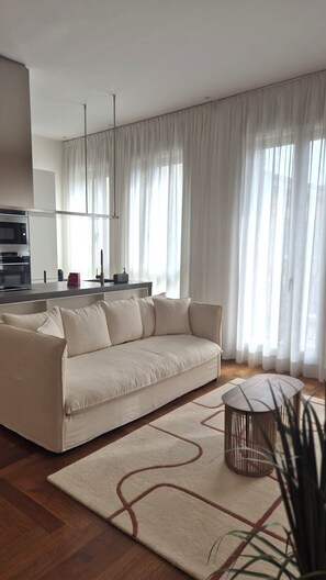 A modern living room with a sofa, a coffee table, and a kitchen in the background. - Manzoni44Suite (Milan)