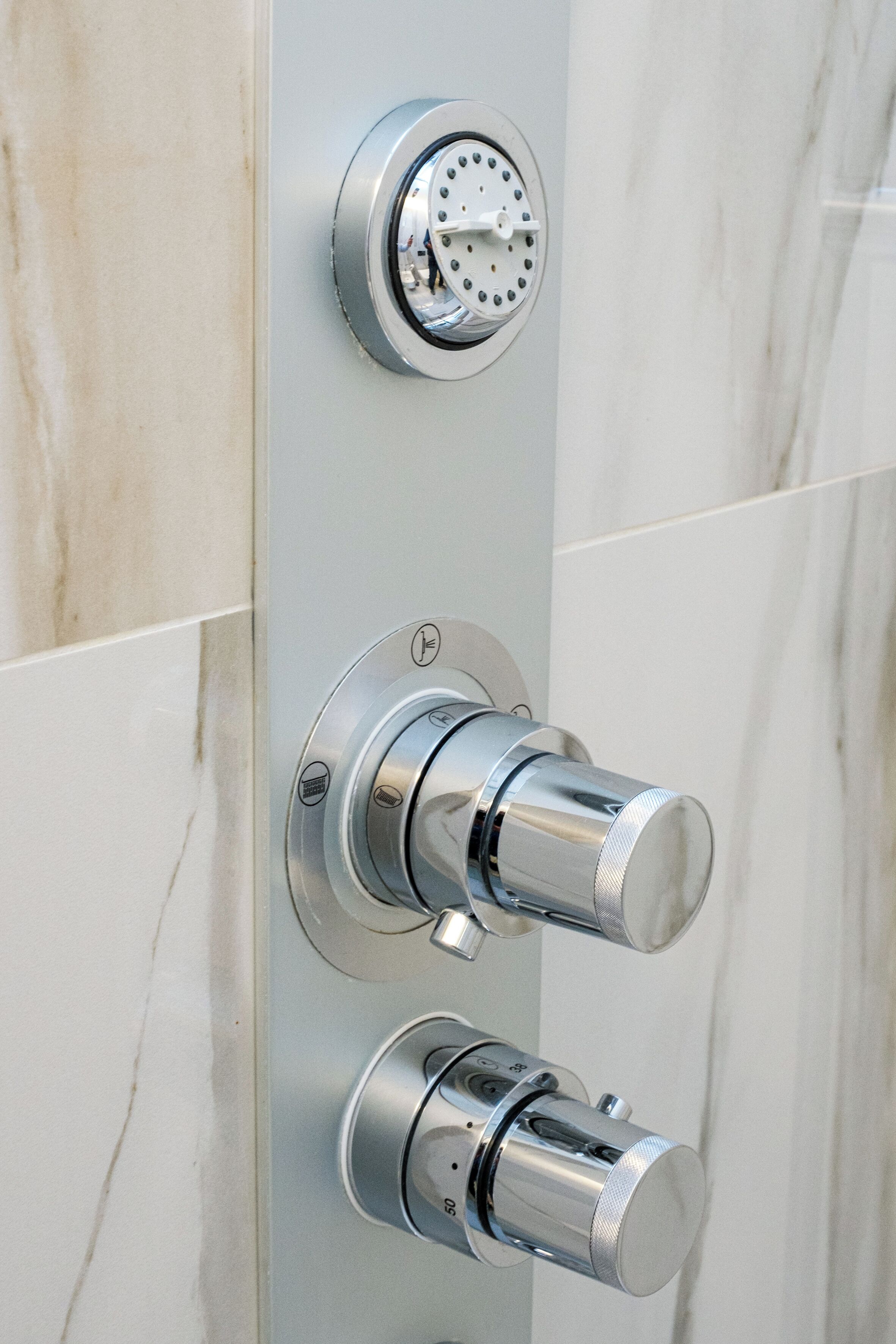 A bathroom with a modern shower control panel and a wall-mounted faucet.