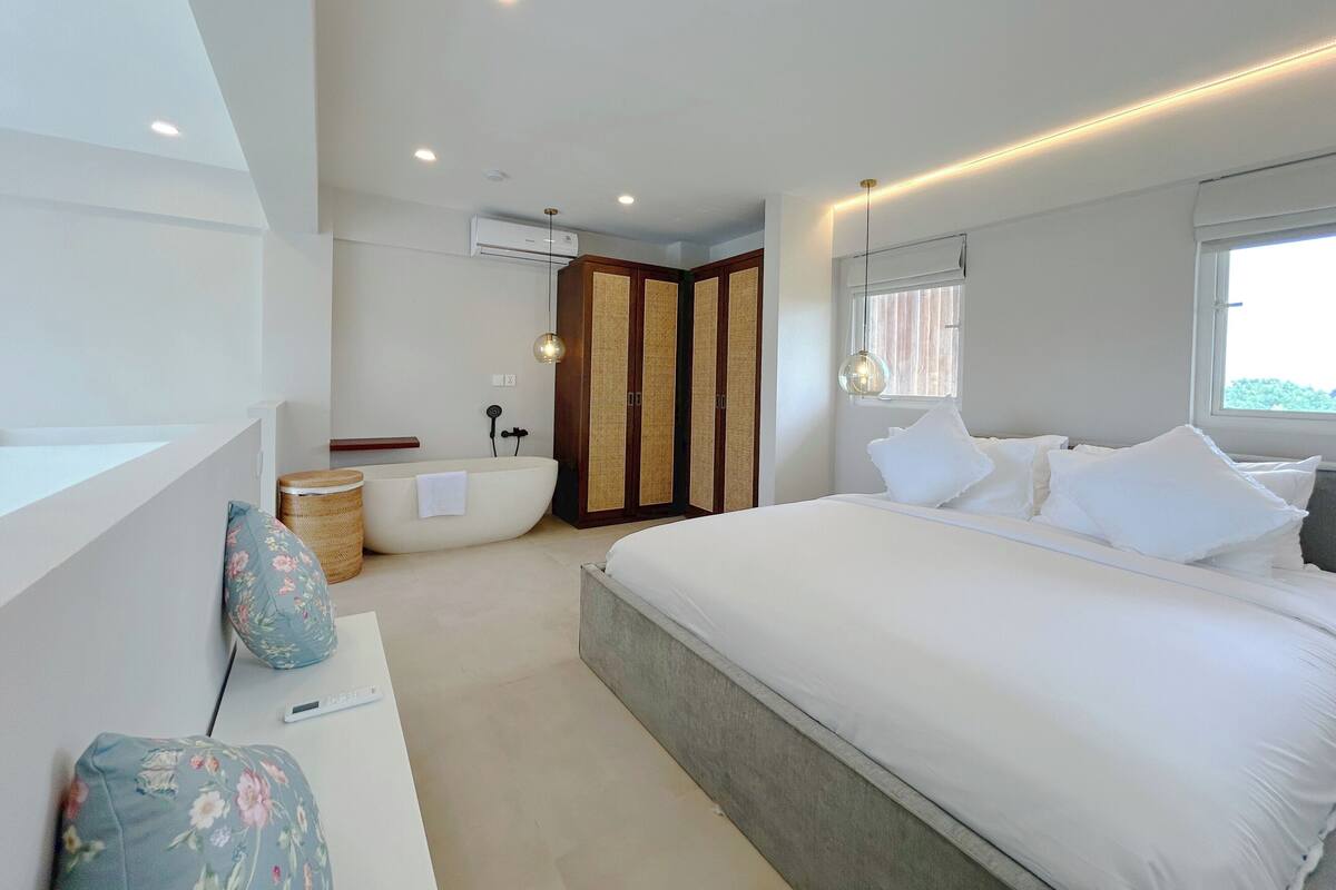 Een moderne slaapkamer met een groot bed, een ingebouwd bad en een groot raam.