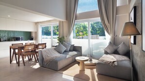A modern living room with a grey sofa, a round coffee table, and a dining area with wooden chairs and a table. - A.K.A Tropicana Bingin (Pecatu)