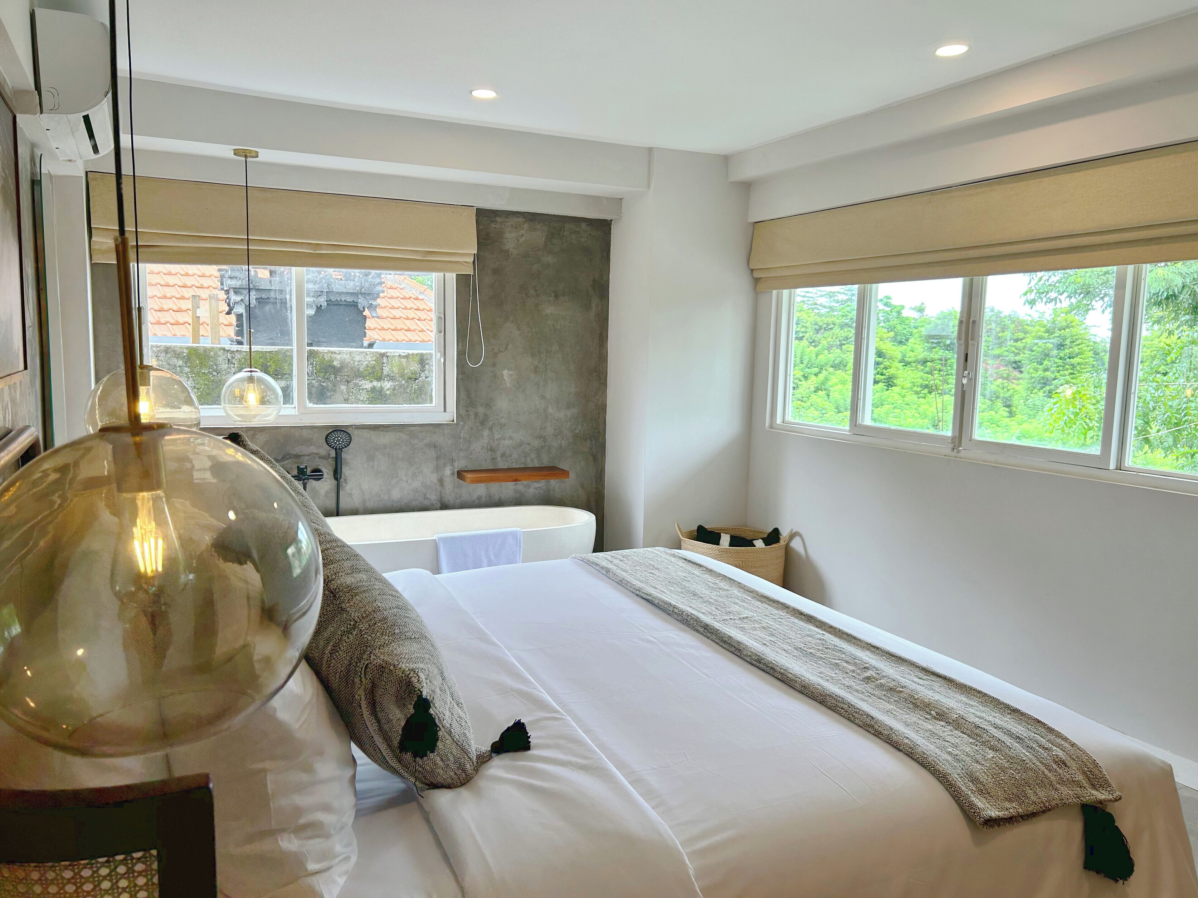 Un dormitorio moderno con una cama grande, una bañera integrada y vistas a la vegetación.