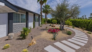 A modern house with a landscaped garden, including cacti, palm trees, and a winding stone path. - Escoba Ranch, spectacular property, large yard and citrus grove, License #064010 (Palm Springs)
