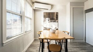 A dining area with a wooden table and chairs, a white bowl, and a cityscape view through large windows. - #StayinMyDistrict Depot Bench Near Downtown BSU (Boise)