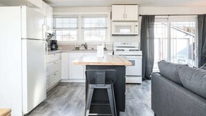 A compact kitchen with white cabinets, a central island, a microwave, and a stove. - #StayinMyDistrict Depot Bench Near Downtown BSU (Boise)