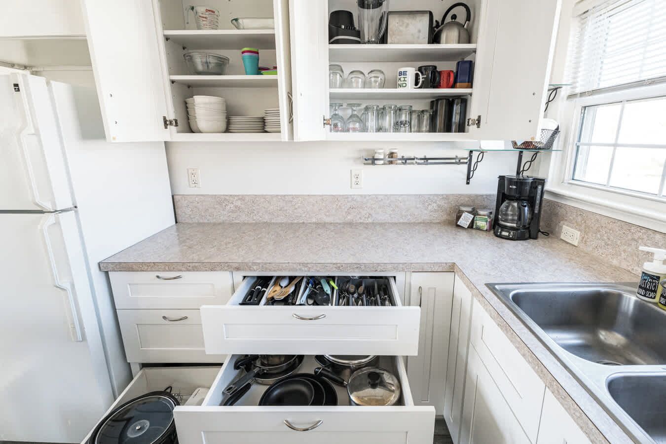 Een keuken met witte kasten, een aanrecht, een spoelbak en een fornuis.