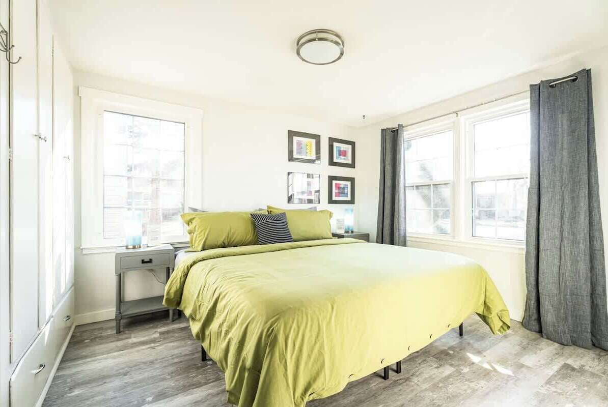 A bedroom with a bed, two bedside tables, a window, and a door.
