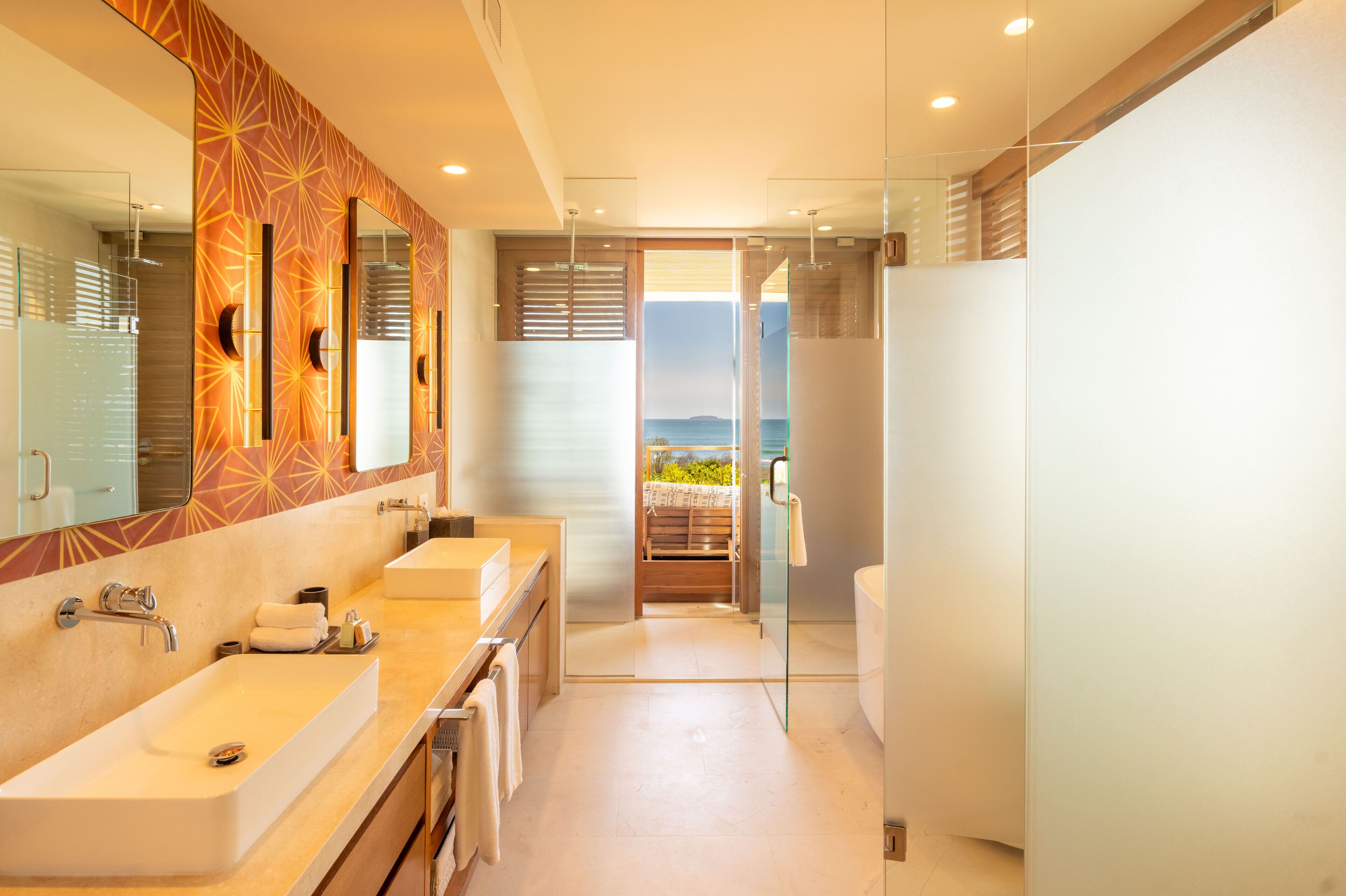 Une salle de bain moderne avec un grand miroir, deux lavabos et une douche à l’italienne.