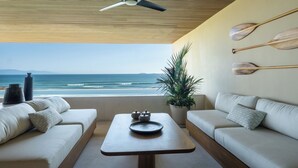 Ein modernes Wohnzimmer mit Meerblick, einem Deckenventilator und einem Holztisch.
