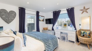 Une chambre à coucher avec un lit, un bureau, une chaise et une grande fenêtre avec des rideaux.