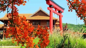 A traditional wooden building with a red torii gate in front. - Baan mansin (Pak Chong)