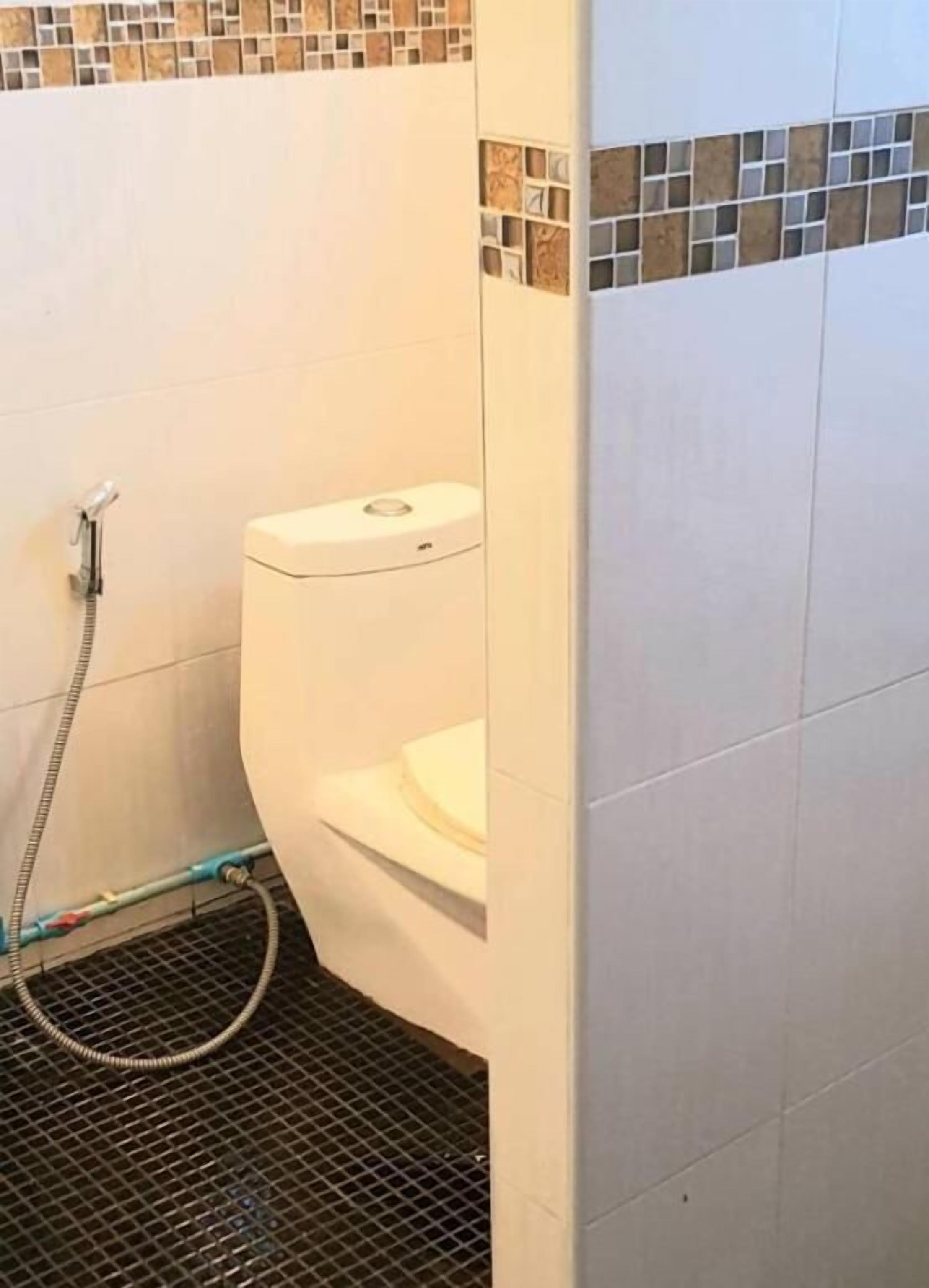 Ein Badezimmer mit Toilette, Dusche und Fliesenboden.