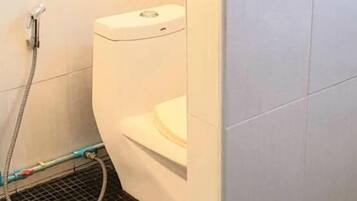 Ein Badezimmer mit Toilette, Dusche und Fliesenboden.