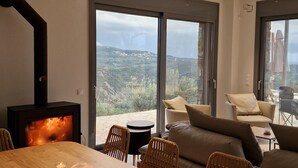 Een moderne woonkamer met een open haard, een eettafel en een zithoek.