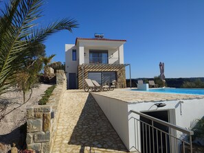 Una casa moderna de dos pisos con un sendero de piedra que conduce a una zona de piscina.