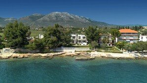 A coastal town with buildings near the water, a mountain in the background, and clear skies.