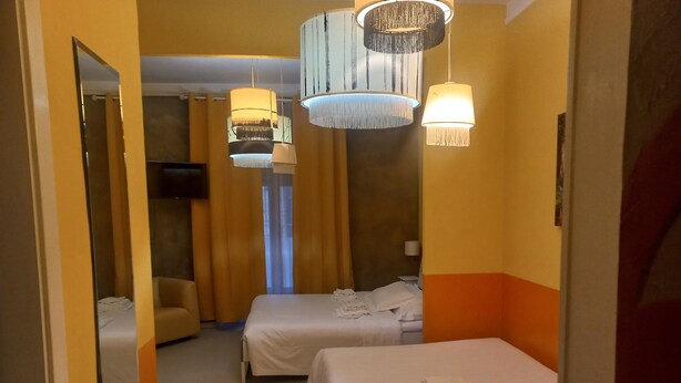 A hotel room with two beds, a sofa, and a TV. - Premium quadruple room Vatican  (Roma)