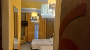 A hotel room with two beds, a TV, and a chandelier. - Premium quadruple room Vatican  (Roma)