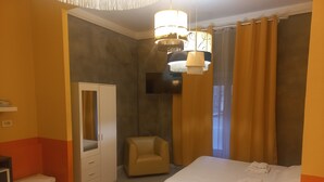 A hotel room with a bed, a chair, a wardrobe, a TV, and a small table. - Premium quadruple room Vatican  (Roma)