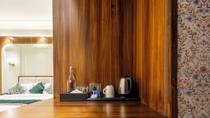 A hotel room with a wooden panel wall, a coffee maker, a bottle, and a tray with a tissue box and a cup. - The Nathuli Manor (Mussoorie)