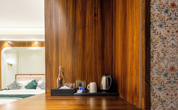 A hotel room with a wooden panel wall, a coffee maker, a bottle, and a tray with a tissue box and a cup. - The Nathuli Manor (Mussoorie)