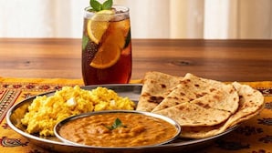 A meal with flatbreads, a bowl of dal, and a plate of scrambled eggs, accompanied by a glass of iced tea with lemon slices. - The Nathuli Manor (Mussoorie)