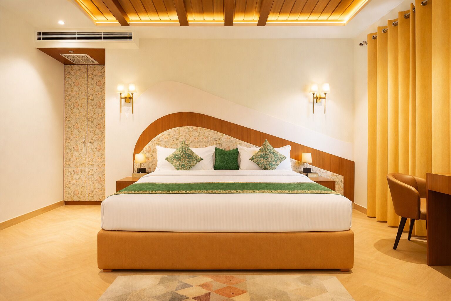 A modern hotel room with a large bed, two bedside tables with lamps, a wooden headboard, and a seating area with a chair and table.