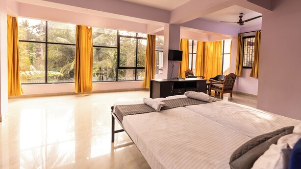 Um quarto espaçoso com uma cama grande, uma escrivaninha com cadeira e um ventilador de teto.
