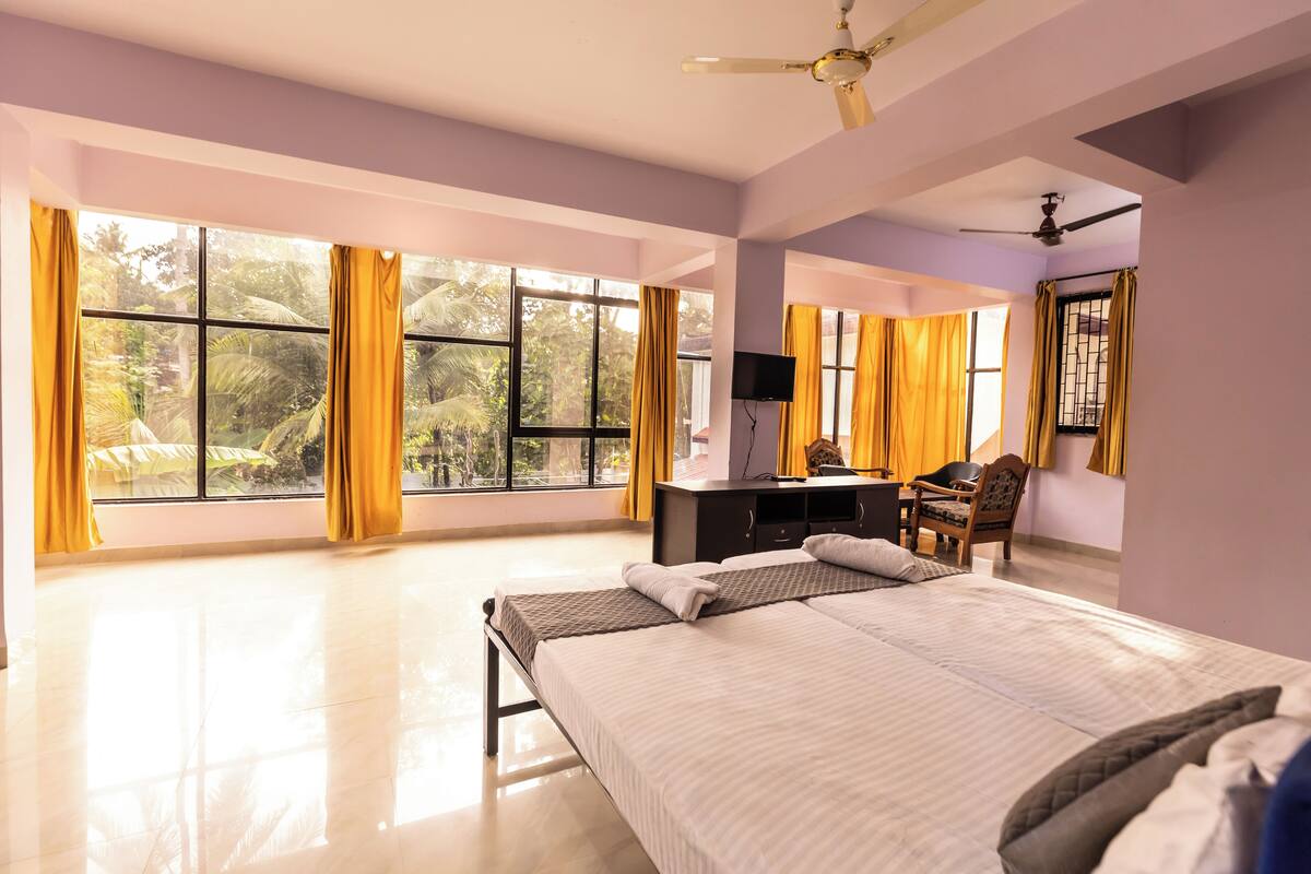 A spacious bedroom with a large bed, a desk with a chair, and a ceiling fan.