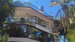 Um hotel com entrada de tapete vermelho, cortinas brancas e varanda.