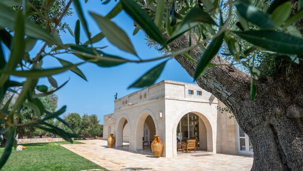 A building with a courtyard, large vases, and a tree. - Stunning luxury retreat with large pool. Great location near the sea in Puglia (Carovigno)