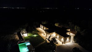 A well-lit residential property at night with a swimming pool, a driveway, and a garage. - Stunning luxury retreat with large pool. Great location near the sea in Puglia (Carovigno)