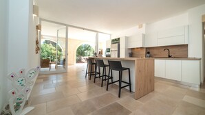 A modern kitchen with a central island, bar stools, and a view to an outdoor patio. - Stunning luxury retreat with large pool. Great location near the sea in Puglia (Carovigno)